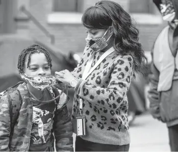  ?? ANDREW RUSH/PITTSBURGH POST-GAZETTE ?? Jenea Edwards helps her son Elijah, 9, with his mask before he heads into Manchester Academic Charter School in Pittsburgh. March 29 was the first day of in-person learning via a hybrid schedule.