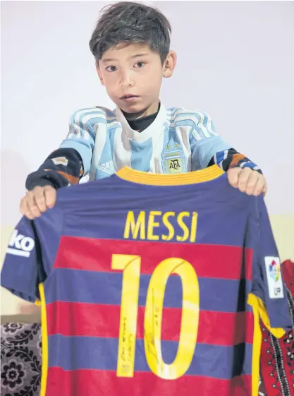  ??  ?? Murtaza Ahmadi shows a shirt signed by Lionel Messi at his relative’s home in Kabul.