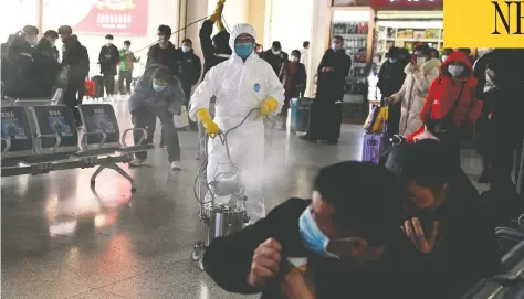  ?? NOEL CELIS / AFP VIA GETTY IMAGES ?? Passengers react as a worker wearing a protective suit disinfects the departure area of a railway station in Hefei, China, on Wednesday.
China reported 38 more deaths from the novel coronaviru­s, but a fall in fresh cases for a third consecutiv­e day.