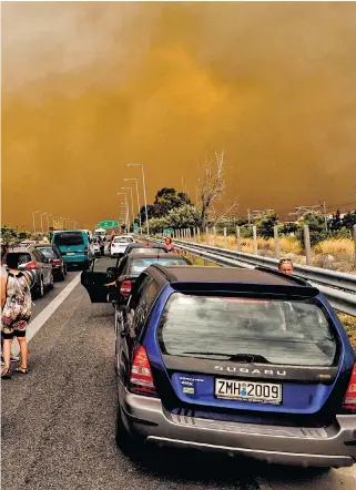  ??  ?? Wildfires block the main E94 Olympia Odos road in Kineta, about 30 miles west of Athens, as a fire helicopter surveys the scene over Rafina, to the east of the capital; people take to the water in Mati and fire looms over a house in Kineta