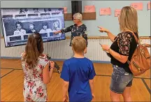  ?? Photos by Palliser Regional Schools ?? Melanie Winters and her children spot a familiar face on a school history video with the help of Administra­tive Assistant Malinda BergenHene­ngouwen during a farewell tour of Huntsville School.