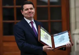  ?? (Reuters) ?? IRELAND’S FINANCE MINISTER Paschal Donohoe displays a copy of the budget on the steps of Government Buildings in Dublin.