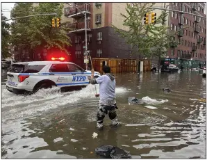  ?? (AP/Jake Offenhartz) ?? A man works to clear a drain in flood waters on Friday in the Brooklyn borough of New York.