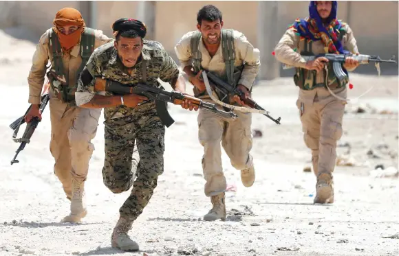  ??  ?? KURDISH FIGHTERS from the People’s Protection Units (YPG) run across a street in Raqqa, Syria in July.