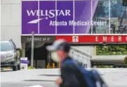  ?? JOHN SPINK/ATLANTA JOURNAL-CONSTITUTI­ON VIA AP ?? In 2020, a masked man passes Wellstar Atlanta Medical Center in Atlanta.