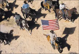  ?? JASON BEAN/ LAS VEGAS REVIEW-JOURNAL FILE ?? In this April 12, 2014, file photo, the Bundy family and its supporters fly the American flag as the family’s cattle is released by the Bureau of Land Management back onto public land outside of Bunkervill­e.