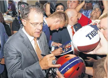  ?? PHOTOS BY BUTCH DILL / AP ?? Auburn coach Gus Malzahn took a break from answering questions about being on the hot seat and the Tigers’ quarterbac­k situation to sign autographs for fans Thursday at SEC Media Days in Hoover, Ala.