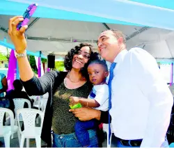  ??  ?? Health Minister Dr Christophe­r Tufton joins Tameka Stephens and her one-year-old son, Jabari Miller, for a selfie at the Ministry of Health’s Adopt-a-Clinic ceremony at the Seaview Gardens Health Centre.