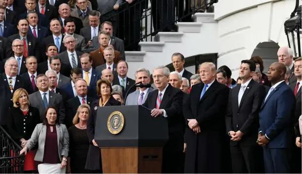  ?? (Olivier Douliery/Abaca Press/TNS) ?? SENATE MAJORITY Leader Mitch McConnell speaks as President Donald Trump looks on during a celebratio­n of the tax bill’s passage with members of the House and Senate last week in Washington, DC.