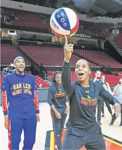  ?? KENNETH K. LAM/BALTIMORE SUN ?? Maryland senior guard Ieshia Small learns how to spin the ball during a surprise visit from Harlem Globetrott­er Zeus McClurkin. Small, who also coaches a Maryland men’s club team, has played in all 32 games this season, averaging 9.3 points and 3.7...