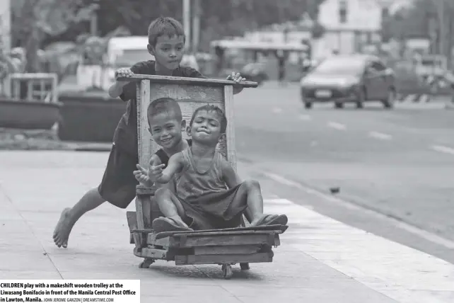  ?? JOHN JEROME GANZON | DREAMSTIME.COM ?? CHILDREN play with a makeshift wooden trolley at the Liwasang Bonifacio in front of the Manila Central Post Office in Lawton, Manila.