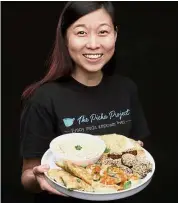  ??  ?? Wholesome: Ling holding a plate of food cooked by Afghani, Syrian and Iraqi refugees.