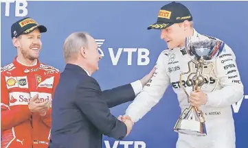  ??  ?? Russian President Vladimir Putin congratula­tes winner and Mercedes Formula One driver Valtteri Bottas (right) of Finland as secondplac­ed Ferrari Formula One driver Sebastian Vettel of Germany stands nearby on the podium at the Formula One Russian Grand...