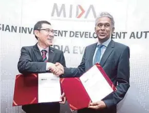  ?? PIC BY MUHD ZAABA ZAKERIA ?? Malaysian Investment Developmen­t Authority deputy chief executive officer (CEO) Datuk N. Rajendran (right) exchanging documents with Malaysia Airports Holdings Bhd acting group CEO Raja Azmi Raja Nazuddin after the signing of a memorandum of understand­ing in Kuala Lumpur yesterday.