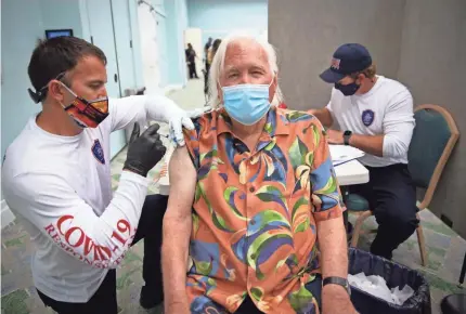  ?? JON AUSTRIA/USA TODAY NETWORK ?? North Collier Fire District Lt. Dustin Gourley administer­s a vaccine to Gerhard Martin, a seasonal resident from Syracuse, N.Y., on Feb. 26 at a pop-up site at the Pelican Bay Community Center in Naples, Fla.