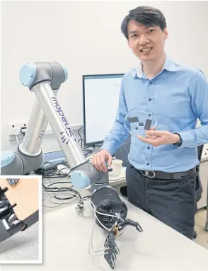  ?? REUTERS PHOTOS BY ?? Assistant Professor Benjamin Tee poses holding samples of the AiFoam next to a robotic arm at the National University Singapore.