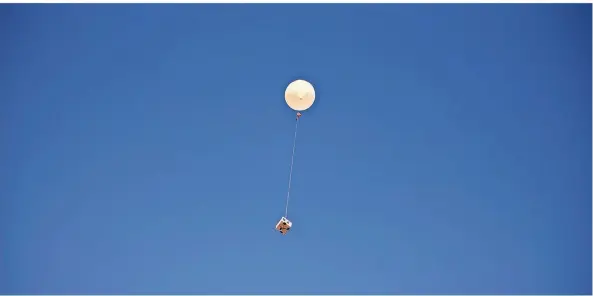  ??  ?? Der mit Heliumgas gefüllte Ballon wird in die Luft gelassen. An einer 18 Meter langen Schnur hängen Fallschirm und Sonde.