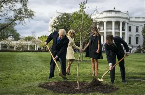  ?? Washington Post photo by Jabin Botsford ?? President Donald Trump and French President Emmanuel Macron, along with first lady Melania Trump and Mr. Macron's wife, Brigitte, plant a tree on the South Lawn of the White House on April 23, 2018.
