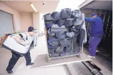  ?? MARK HUMPHREY/AP ?? Troy Adams, left, and Levon Marlow of VIP Moving and Storage in Nashville, Tenn., load the Tennessee Titans players’ bags as the team prepares for a two-week stint in California and Arizona.