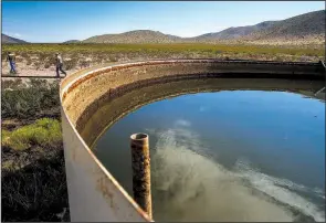  ?? The Houston Chronicle/MICHAEL CIAGLO ?? Ranch manager Will Hughes (left) and Apache Ranch manager George Strickhaus­en walk past a tank holding water pumped from a well on the Apache Ranch in Van Horn, Texas, in mid-July.