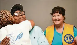  ??  ?? Dawn Wells (left) gives Sara Randall of Atlanta (center) a hug as Nancy Morton-Linek of Conyers, a Lions Club volunteer, watches at Dawn Wells Fitness in Covington recently.