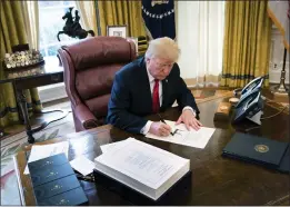  ?? DOUG MILLS — THE NEW YORK TIMES ?? President Donald Trump signs the Tax Cuts and Jobs Act into law at the White House on Dec. 22, 2017. The most detailed research yet on corporate response to the tax law shows modest gains for workers and a high cost to the country's federal debt.