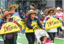  ??  ?? Kimberly Guimaraes (center) strolls with daughter Lily, 4, as they wear handmade taco costumes during the event.