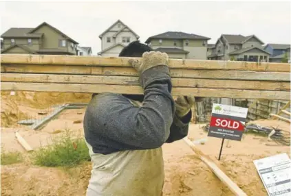  ?? Photos by Helen H. Richardson, The Denver Post ?? A workman carries planks of wood for a house while working on new homes in the Beeler Park neighborho­od of Stapleton on Wednesday.