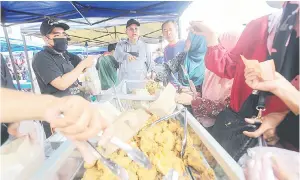  ?? — Gambar Bernama ?? TURUN PADANG: Annuar (dua kiri) beramah mesra bersama peniaga dan pengunjung pasar tani ketika mengadakan tinjauan harga barangan makanan di Pasar Ketereh di Kota Bharu, semalam.