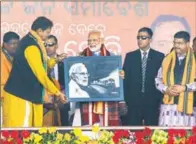  ??  ?? Prime Minister Narendra Modi being presented a portrait during a public meeting at Patharchep­a in Bolangir, Odisha, on Tuesday.