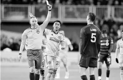  ?? AP ?? Referee Scott Bowman (left) shows a yellow card to Toronto FC defender Kevin Long (5) while Atlanta United forward Tyler Wolff (28) looks on during the first-half of an MLS football match in Toronto on Saturday.