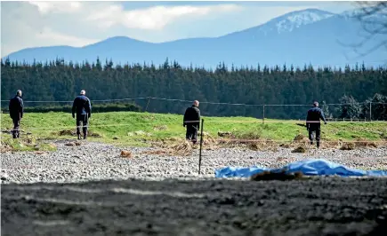  ?? PHOTO: DAVID WALKER/STUFF ?? Police officers search the scene near the Waimakarir­i River where a body was found on Monday night.