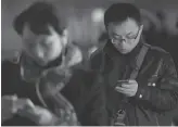  ?? Peter Parks / AFP / Getty Images ?? People check their devices in a metro station in Shanghai in 2014. WeChat’s messaging service and payments service app is popular in China.