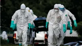  ??  ?? Cemetery workers carry the coffin of a man who died of the disease caused by the new coronaviru­s (COVID-19)