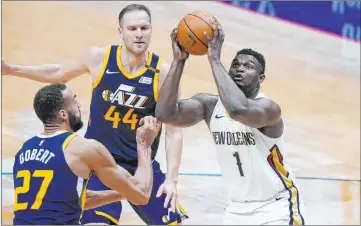  ?? Gerald Herbert The Associated Press ?? New Orleans forward Zion Williamson shoots as Utah center Rudy Gobert and forward Bojan Bogdanovic try to defend.