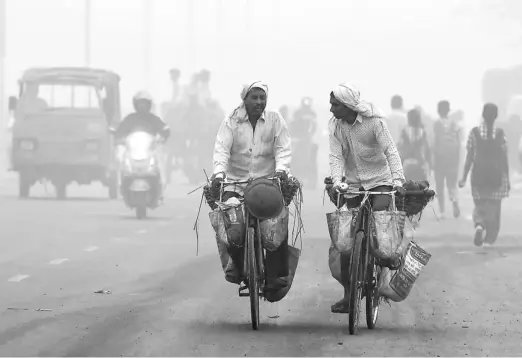  ?? — Gambar AFP ?? TERCEKIK: Para pengguna jalan raya meredah asbut tebal di New Delhi, semalam dalam perjalanan ke tempat kerja.