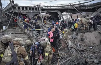  ?? (AFP) ?? People cross a destroyed bridge as they evacuate the city of Irpin, northwest of Kyiv, on Saturday.