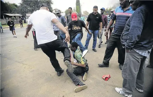  ?? / THULANI MBELE ?? A man is assaulted by the community after he robbed another resident of a phone during a protest. Residents barricaded James Road with burning tyres and rocks as clashes with the police continued.