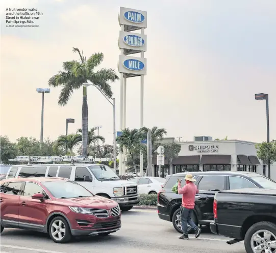  ?? AL DIAZ adiaz@miamiheral­d.com ?? A fruit vendor walks amid the traffic on 49th Street in Hialeah near Palm Springs Mile.