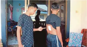  ??  ?? MUHAMMAD Amru menunjukka­n belakang badan adiknya yang ditikam suspek.