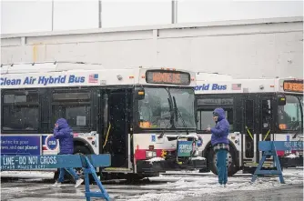  ?? Erin Hooley/associated Press ?? Snow falls as migrants are housed by the city of Chicago in “warming buses” during the winter storm on Friday. Illinois Gov. J.B. Pritzker urged Gov. Greg Abbot to pause busing during the storm.