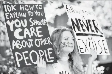  ?? NWA Democrat-Gazette/CHARLIE KAIJO ?? Megan Hansen of Siloam Springs holds signs during a rally Saturday at the downtown square in Fayettevil­le. “It’s about encouragin­g people who feel the same way we do but don’t think we can change anything,” she said for why she attended the event.