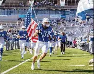  ?? Paul Hokanson / Associated Press ?? Buffalo’s Damian Jackson carries the American flag as the team takes the field before a game against Toledo on Oct. 22.