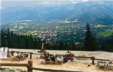  ??  ?? Tourists sitting on beach deck chairs overlookin­g the Tatra Mountains in Zakopane.