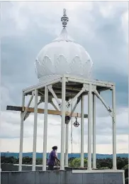  ??  ?? Kulwant Singh waits to hoist one of 54 small domes onto the roof of the Gurdwara Shaheedgar­h Sahib Hamilton Thursday.