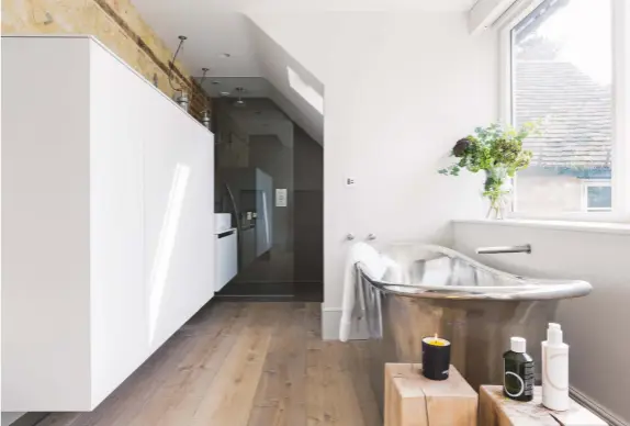  ??  ?? ADJOINING BATHROOM
In this scheme (above), kitchen cabinets were used to provide ample storage and raised off the floor to prevent the space from feeling like a corridor. A modern walk-in shower makes best use of the pitched ceiling at the far end of...