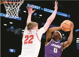  ?? SARAH STIER/GETTY ?? James Madison guard Xavier Brown, a former Jamestown High star, drives to the basket against Wisconsin forward Steven Crowl during a first-round NCAA Tournament game Friday night in New York.