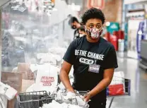  ?? Steve Gonzales / Staff photograph­er ?? Isaiah Gatson sacks groceries in an H-E-B “Be the Change” T-shirt in the supermarke­t chain’s Buffalo Heights store.