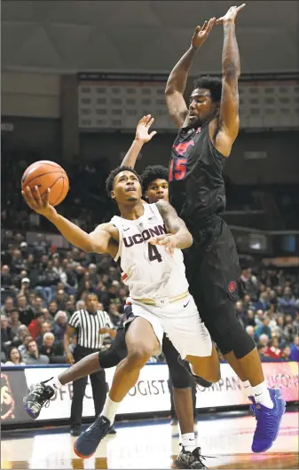  ?? Jessica Hill / Associated Press ?? UConn’s Jalen Adams (4) looks to shoot as he splits between SMU's Feron Hunt and SMU's Isiaha Mike (15) during the second half on Thursday.