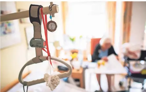  ?? FOTO: JONAS GÜTTLER/DPA ?? Eine Seniorin sitzt hinter einem Krankenbet­t in einer Pflegeeinr­ichtung.